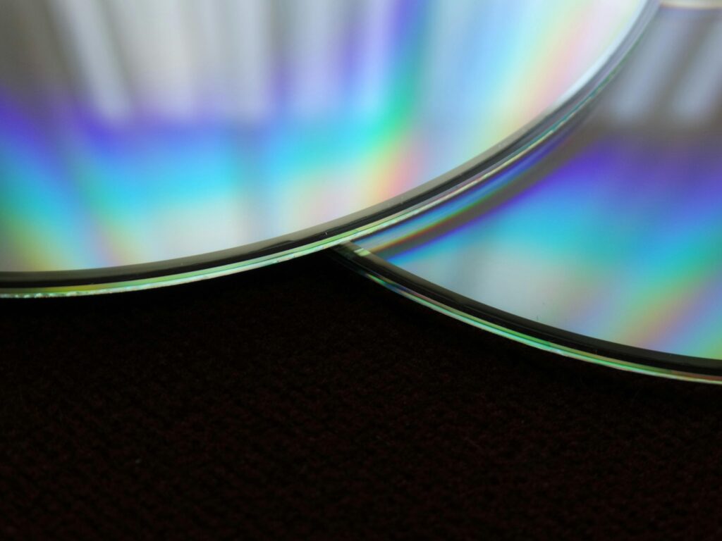 Detailed close-up of two overlapping compact discs showing a colorful rainbow reflection.