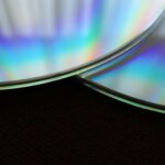 Detailed close-up of two overlapping compact discs showing a colorful rainbow reflection.