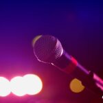 Colorful stage lighting highlights a microphone in a close-up view, perfect for music and performance themes.