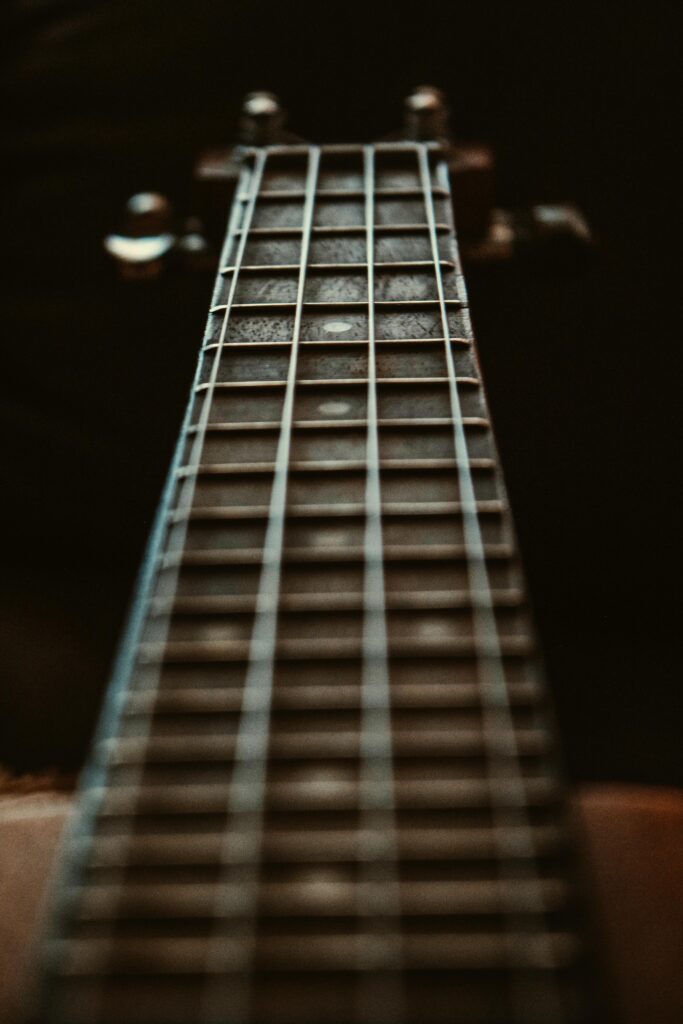 Artistic close-up of a guitar fretboard focusing on the strings and frets with a depth of field effect.