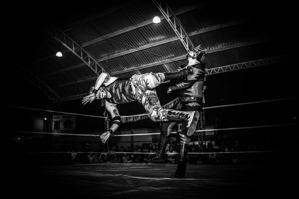 Intense Lucha Libre wrestling match showcasing strength and agility under dramatic lighting.