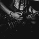 Black and white photo of a guitarist playing during a live performance.