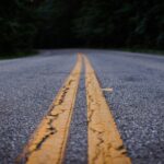 Scenic close-up shot of an empty asphalt road with yellow lines curving through a forested area.