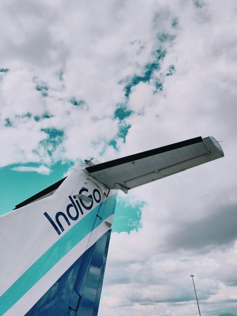 View of an airplane tail against a bright sky filled with clouds, showcasing travel themes.