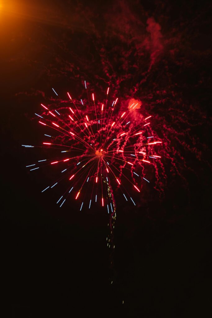 Colorful fireworks display with red and blue sparks in the night sky.
