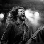 Expressive guitarist passionately performing live on stage in black and white.