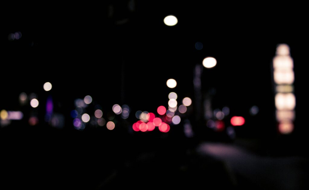 Blurred urban nighttime scene with colorful bokeh lights creating a dreamy effect.